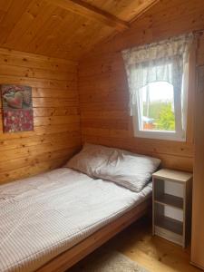 a bed in a log cabin with a window at Domki letniskowe Eliza in Chłopy