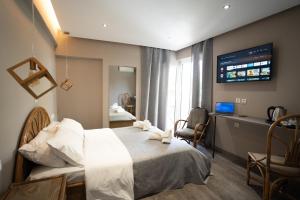 a hotel room with a bed and a tv on the wall at Parthenis Riviera Hotel in Athens