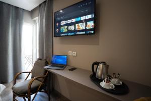 um quarto com uma secretária com um computador portátil e uma televisão em Parthenis Riviera Hotel em Atenas