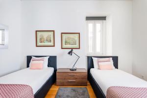 two beds in a room with a nightstand between them at Downtown 75 Prestige in Baixa in Lisbon