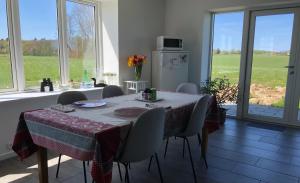 jadalnia ze stołem, krzesłami i oknami w obiekcie Yggdrasil Guest Lodge w mieście Gudhjem