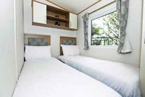 2 camas en una habitación pequeña con ventana en Cleethorpes Pearl Holiday Park en Humberston