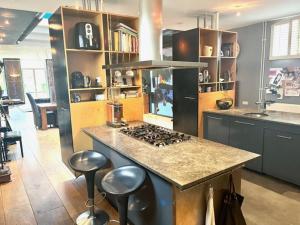 cocina con fogones y encimera con taburetes en Elegant penthouse LOFT of 250 m2 in city centre with huge roofgarden 80 m2, en Ámsterdam