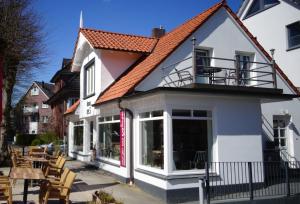 a white house with a balcony and tables at Suite im Huus in Hamburg