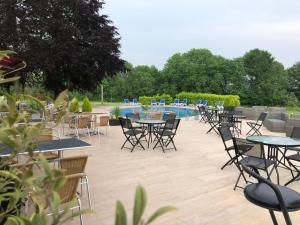 um pátio com mesas e cadeiras e uma piscina em Globales Post Hotel & Wellness em Herstal