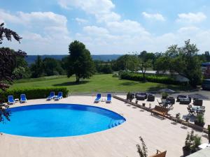 a swimming pool with lounge chairs and a view at Globales Post Hotel & Wellness in Herstal