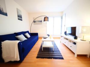 uma sala de estar com um sofá azul e uma televisão em ROCHAMBEAU - Moderne - Face aux Thermes - Parking - em Vichy