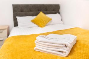 a bed with white towels on it with a yellow blanket at Modern apartment close to city centre with parking in Leeds