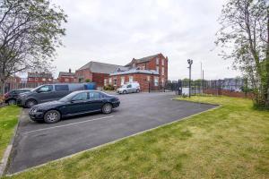 um parque de estacionamento com carros estacionados em frente a uma casa em Modern apartment close to city centre with parking em Leeds