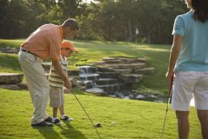 a man teaching a young boy how to play golf at Hyatt Regency Lost Pines Resort and Spa in Cedar Creek