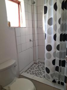 a bathroom with a shower with a toilet and a window at Sunset Guesthouse - Mthatha in Mthatha