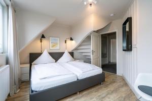 ein Schlafzimmer mit einem Bett mit weißer Bettwäsche und einer Treppe in der Unterkunft Süderliebe in Westerland