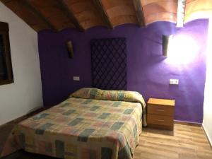 - une chambre avec un lit et un mur violet dans l'établissement Casas Rurales Hoya Calvete, à Yeste
