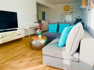 een woonkamer met een witte bank en een televisie bij Ocean Sunset Apartment in Paphos City
