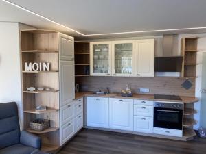 uma cozinha com armários brancos e um forno com placa de fogão em Möwenblick - a57230 em Cuxhaven