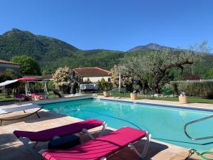 a swimming pool with two lawn chairs and mountains at VILLA ROMAGA in Vernet-les-Bains