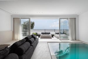 a living room with a couch and a swimming pool at Black Stone Villa in Sounio
