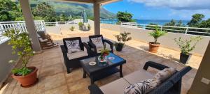 a patio with chairs and a table and the ocean at Harmony Self-Catering Apartments in Beau Vallon