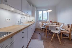 una cocina con armarios blancos y una mesa con sillas. en die weisse Wand en Weissensee