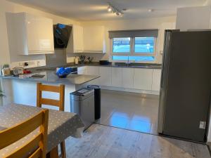 uma cozinha com armários brancos e um frigorífico preto em Remarkable 4-Bed House in St Minver Rock em Wadebridge