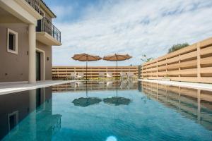 a swimming pool with two umbrellas in the middle at Luxury Villa Chrisi in Svoronata