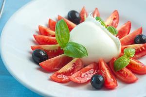 a white plate with strawberries and blueberries and cheese at Hotel Albatros in Ischia