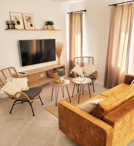 a living room with a couch and chairs and a tv at Pine Point Apartament with terrace, shared pool, tennis court in Pobierowo