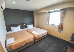 a hotel room with two beds and a window at HOTEL LiVEMAX Kokura Ekimae in Kitakyushu