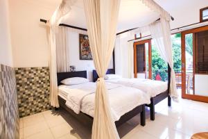 two beds in a bedroom with mosquito nets at Batik Sekar Bali Guest House in Ubud