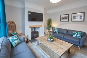 a living room with a blue couch and a table at Host & Stay - King's Cottage in Amble