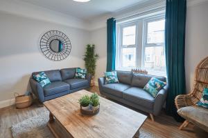 a living room with two blue couches and a table at Host & Stay - King's Cottage in Amble