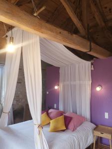 - une chambre dotée d'un lit à baldaquin avec des oreillers jaunes et roses dans l'établissement Castel Mazars, à Castelnau-de-Montmiral
