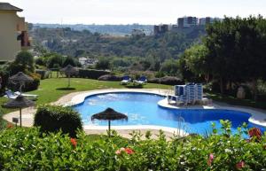 einen Pool mit Stühlen und Sonnenschirmen im Hof in der Unterkunft Fairway Vista La Finca in Málaga