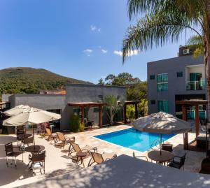 a pool with chairs and umbrellas next to a building at Escarpas Eco Village in Capitólio