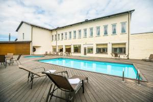 a swimming pool on a deck with chairs and a building at Lõokese Hotell in Käina