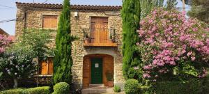 Casa de piedra con balcón y flores rosas en EL PINAR DE BARDENA, en Carcastillo