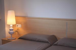 a bedroom with a bed with a lamp and a headboard at Aparthotel Marsol in Castelldefels