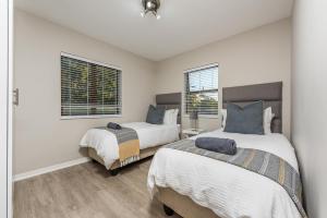 two beds in a room with two windows at Beacon Wharf , George Hay 3 Holiday Accommodation in Mossel Bay