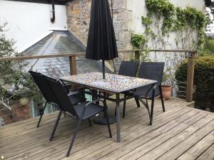 een tafel met stoelen en een parasol op een terras bij Cozy Camborne Studio Retreat with two single beds in Camborne