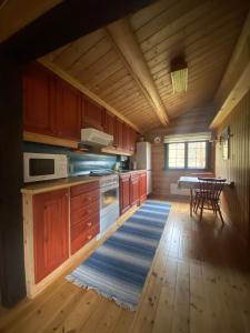 a kitchen with wooden cabinets and a table and a rug at Morgedal Lavvo Camping in Morgedal
