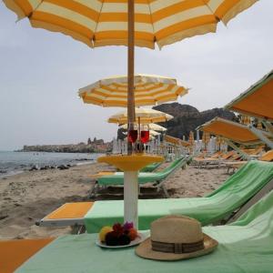 una mesa con sombrero y sombrilla en una playa en Villa Cerniglia Plus, en Cefalú