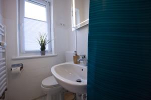 a bathroom with a sink and a toilet and a window at HejU - Parking - Kitchen - Netflix - Kingsize Bett in Lübeck +13 photos