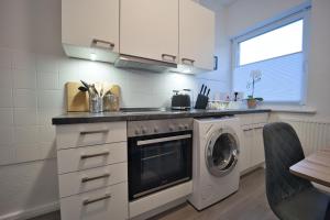 a kitchen with a stove and a washing machine at HejU - Parking - Kitchen - Netflix - Kingsize Bett in Lübeck