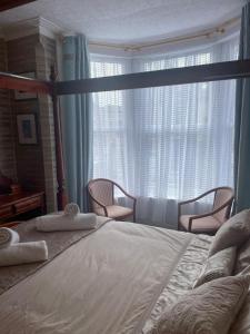 a bedroom with a large bed with two chairs and a window at Riversvale Hotel in Blackpool