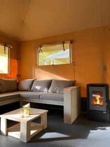 a living room with a couch and a stove at Luxe Safaritent Medley 5 persoons op Camping Rijsterbos in Rijs