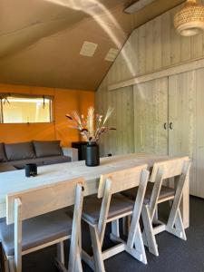 einen Esstisch mit Stühlen und eine Vase aus Blumen in der Unterkunft Luxe Safaritent Medley 5 persoons op Camping Rijsterbos in Rijs