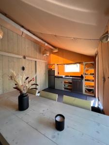 a kitchen with a table with a vase of flowers on it at Luxe Safaritent Medley 5 persoons op Camping Rijsterbos in Rijs