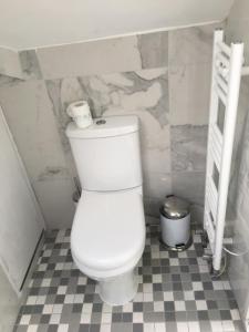 a white toilet in a bathroom with a tiled floor at Rainbow 3BR flat & luxury Spa option in Bournemouth
