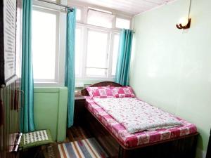Cama pequeña en habitación con 2 ventanas en Basnet Apartment en Darjeeling