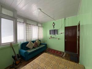 uma sala de estar com um sofá azul e uma guitarra em Basnet Apartment em Darjeeling